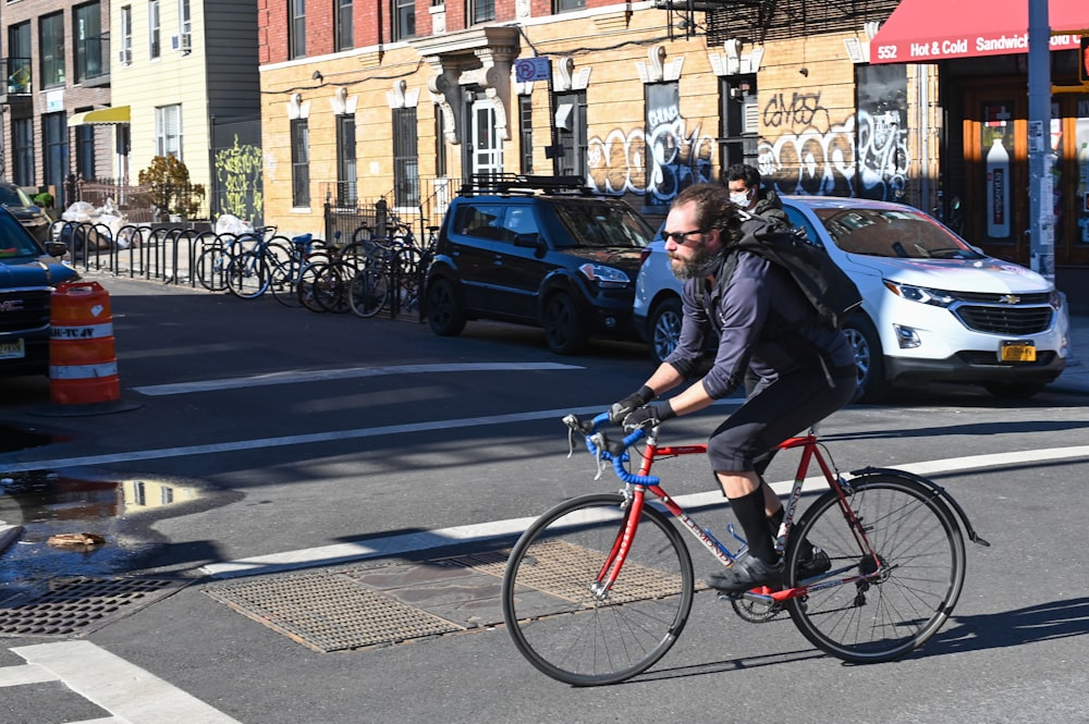 man in black jacket riding on red bicycle on road during daytime