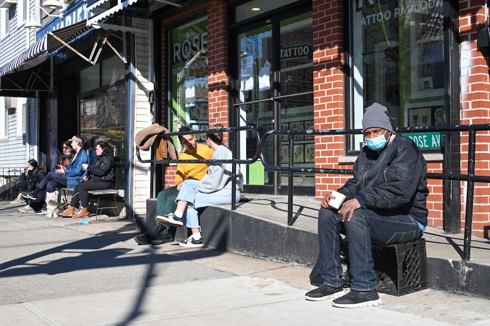 man in blue jacket and blue denim jeans sitting on bench