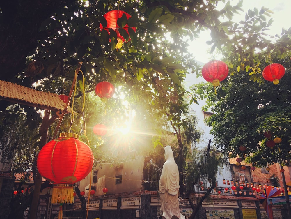 man in white thobe standing under green tree with orange and yellow balloons during daytime