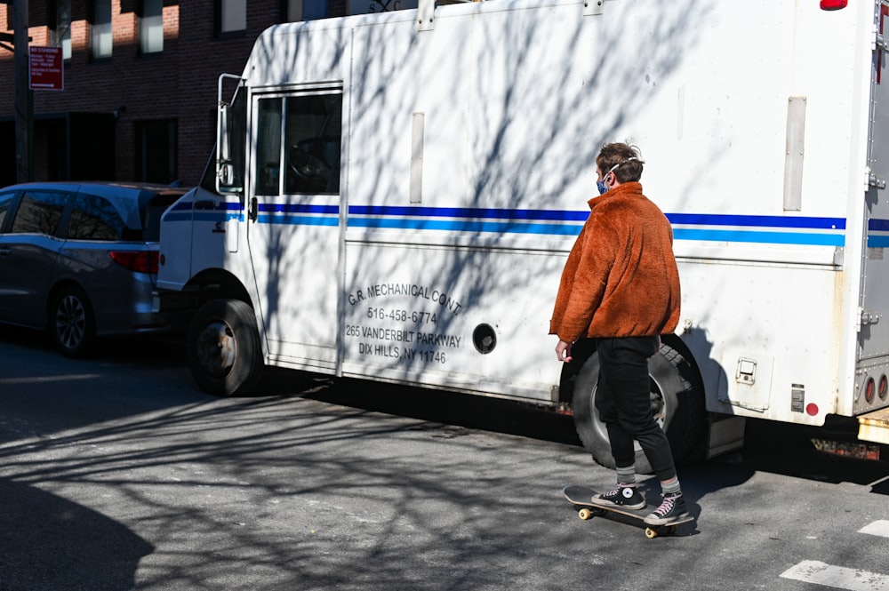 man in orange jacket and black pants riding skateboard
