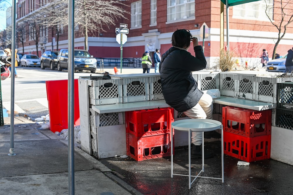 man in black jacket sitting on red plastic seat