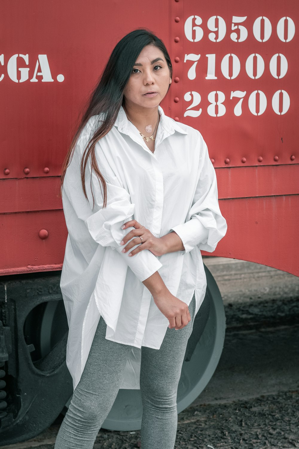 woman in white button up long sleeve shirt standing beside red and black car