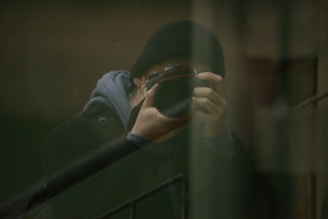 man in gray jacket holding black framed eyeglasses