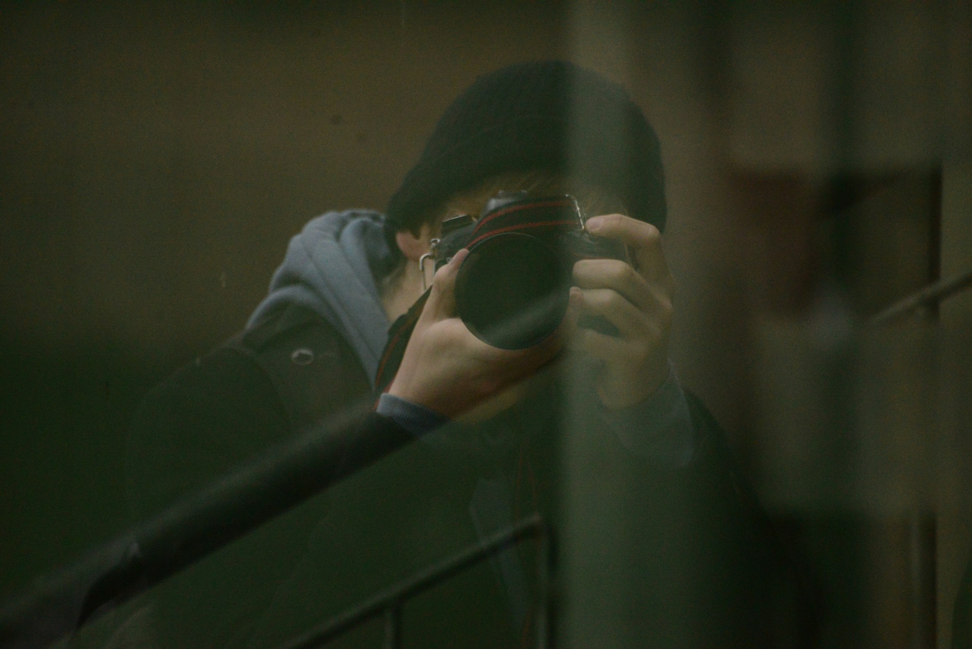 man in gray jacket holding black framed eyeglasses