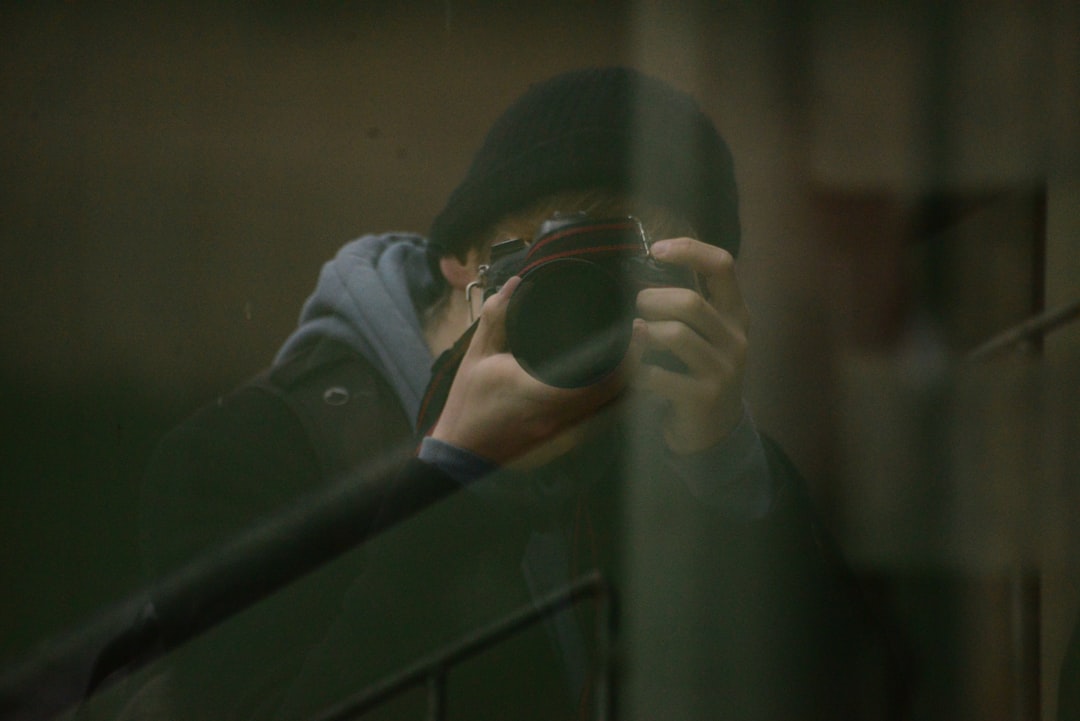 man in gray jacket holding black framed eyeglasses,