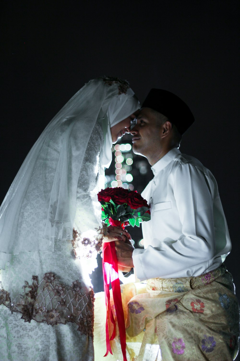 man in white dress shirt and black hat holding bouquet of flowers