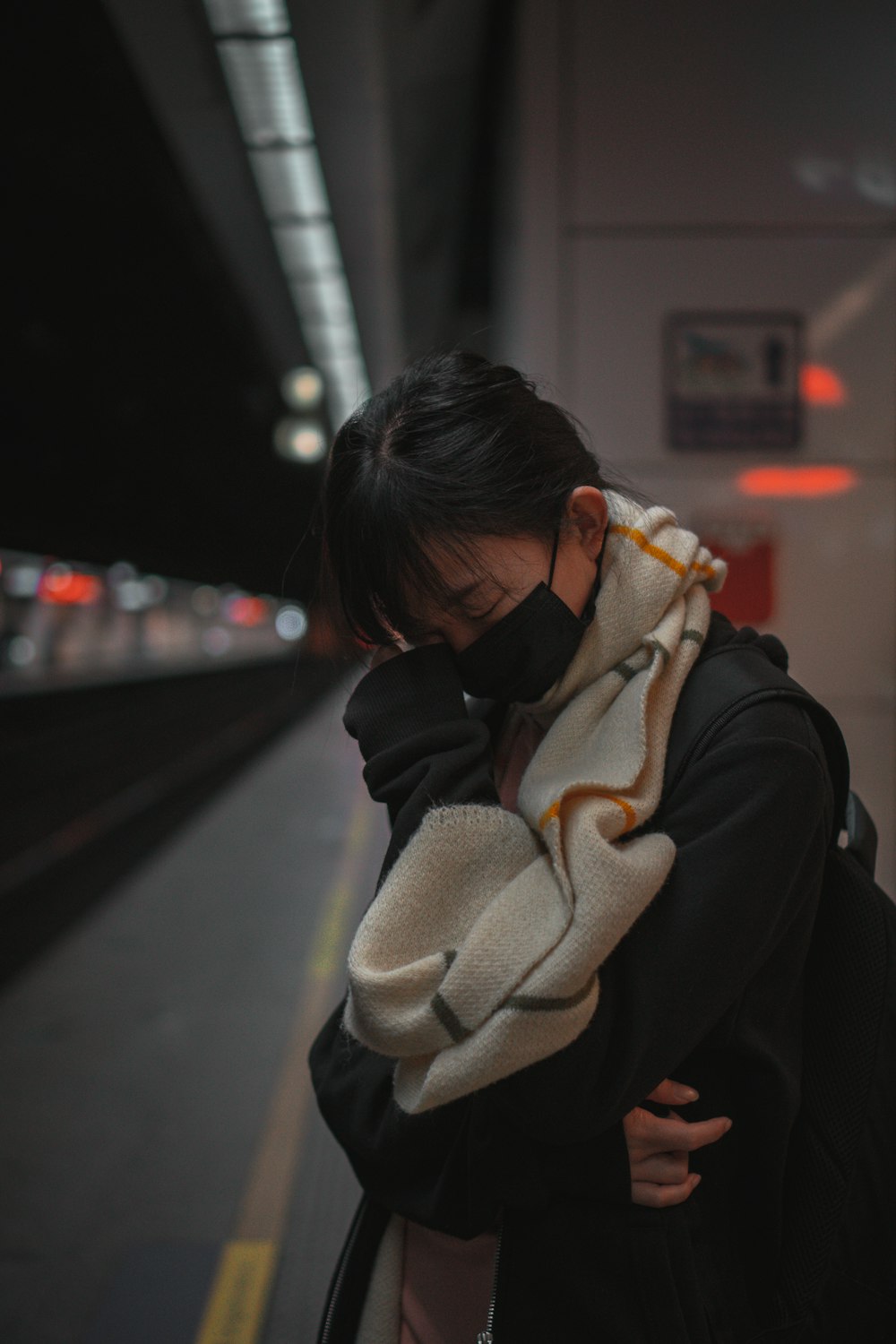 woman in black coat covering her face with gray scarf