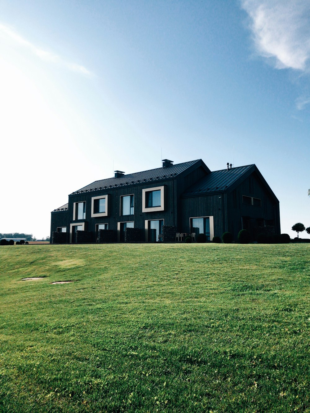 black and white concrete house on green grass field under blue sky during daytime