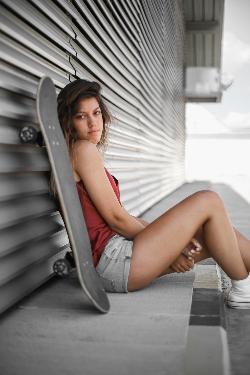 woman in red tank top and blue denim shorts sitting on gray wooden bench