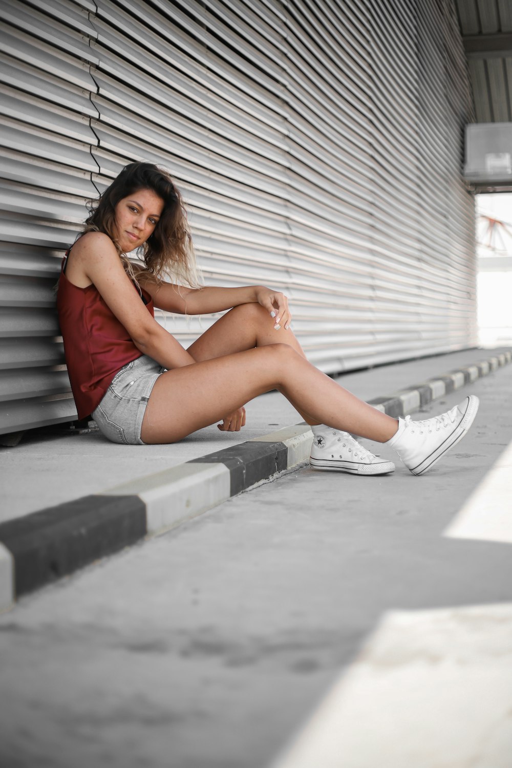 woman in gray denim shorts sitting on gray concrete floor