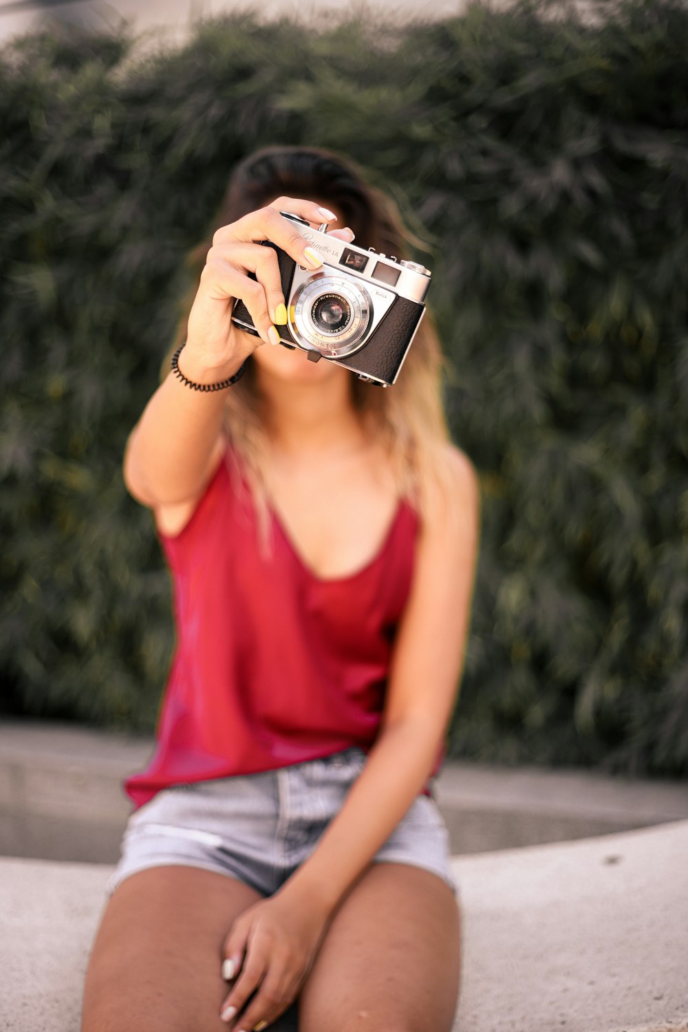 woman in red tank top holding camera
