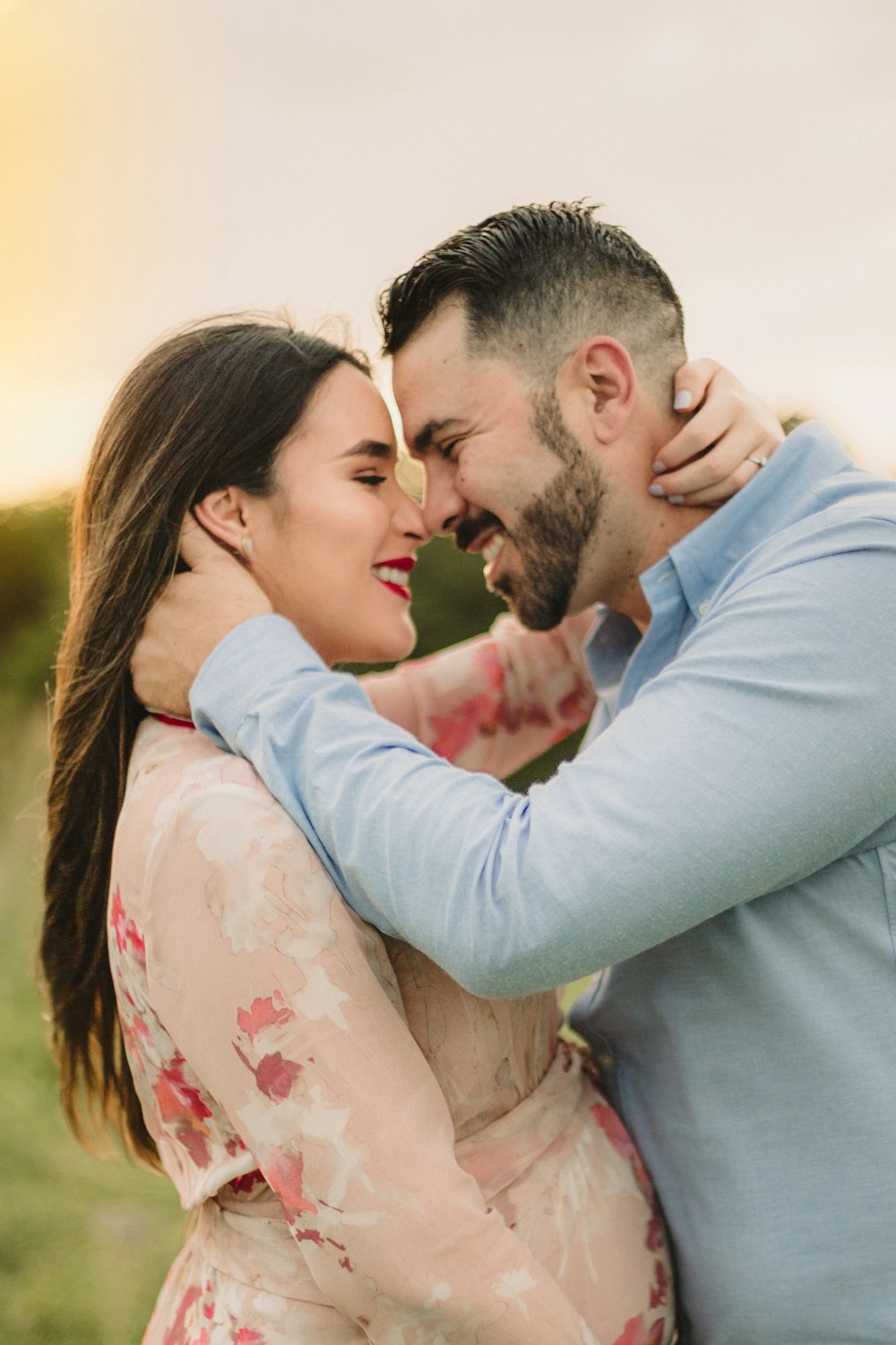 man in blue dress shirt kissing woman in white floral dress