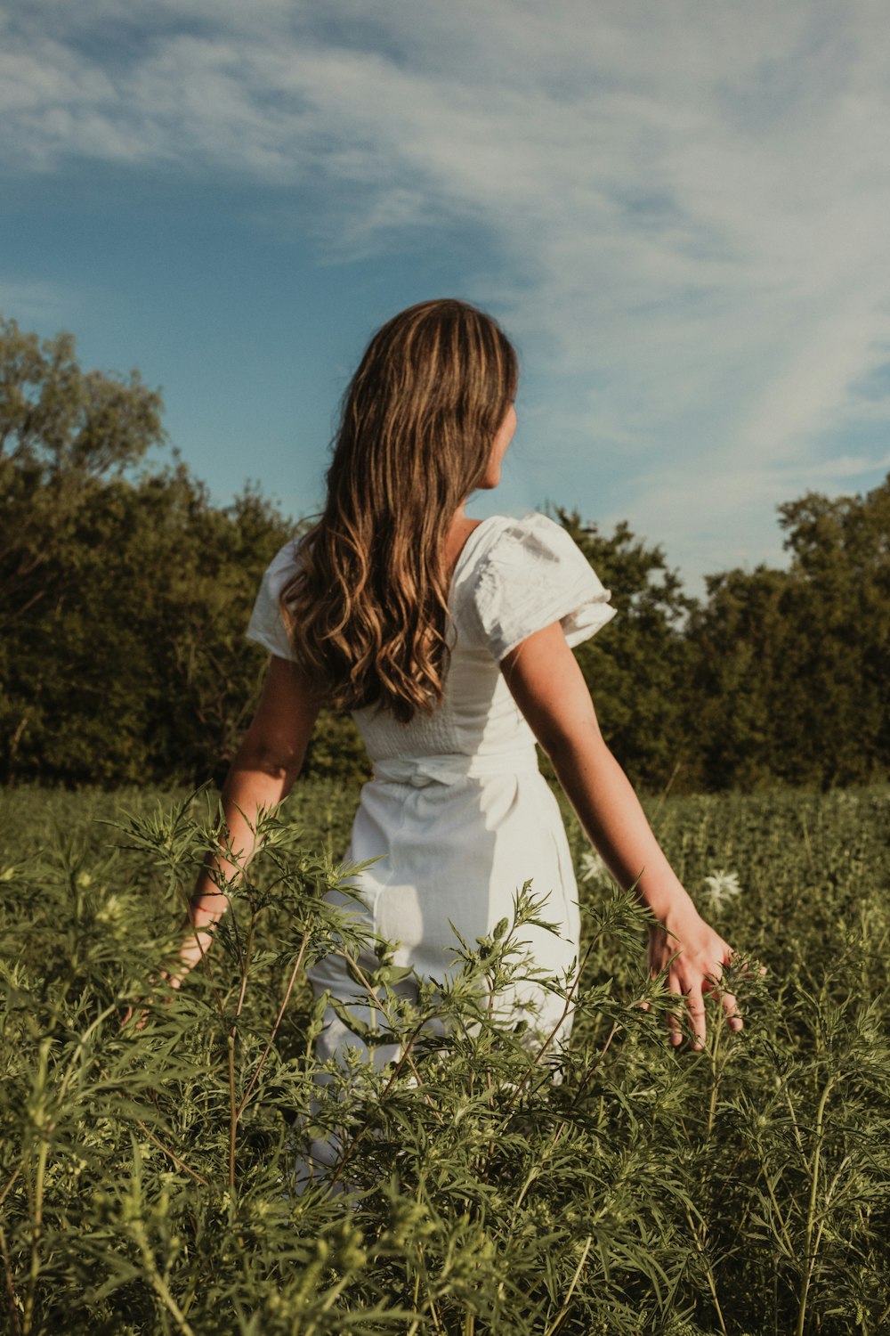 woman in white dress standing on green grass field during daytime