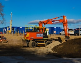 orange and black heavy equipment on brown sand during daytime