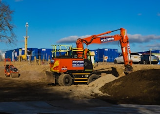 orange and black heavy equipment on brown sand during daytime