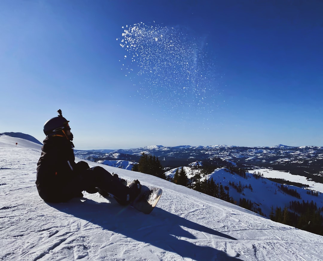 person in black jacket and pants sitting on snow covered ground during daytime