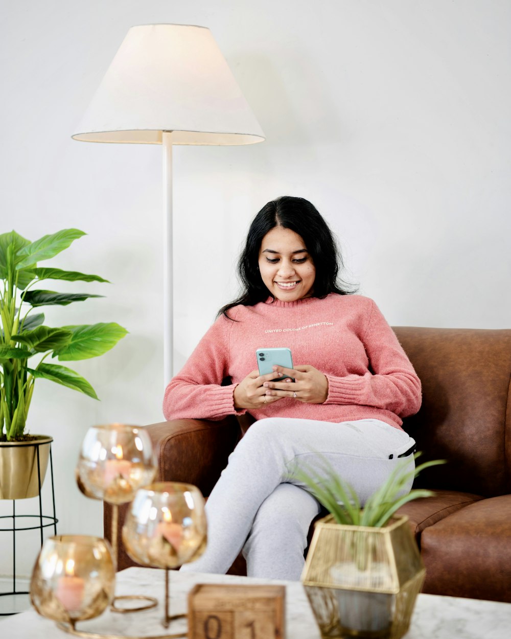 woman in pink long sleeve shirt sitting on brown sofa chair