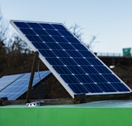 blue and white solar panel on green metal bar during daytime