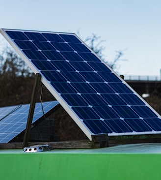 blue and white solar panel on green metal bar during daytime