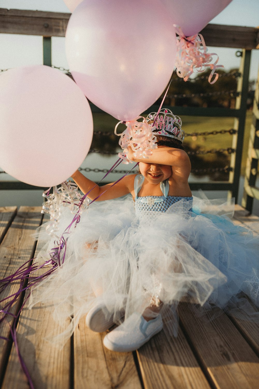 woman in white and pink floral dress holding balloons