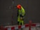 A person, dressed in high-visibility work attire with a bright orange hood, is standing near a red and white barrier in a construction zone. The individual is wearing ear protection and appears to be working in a wet or muddy environment, with some dirt visible on their clothing.