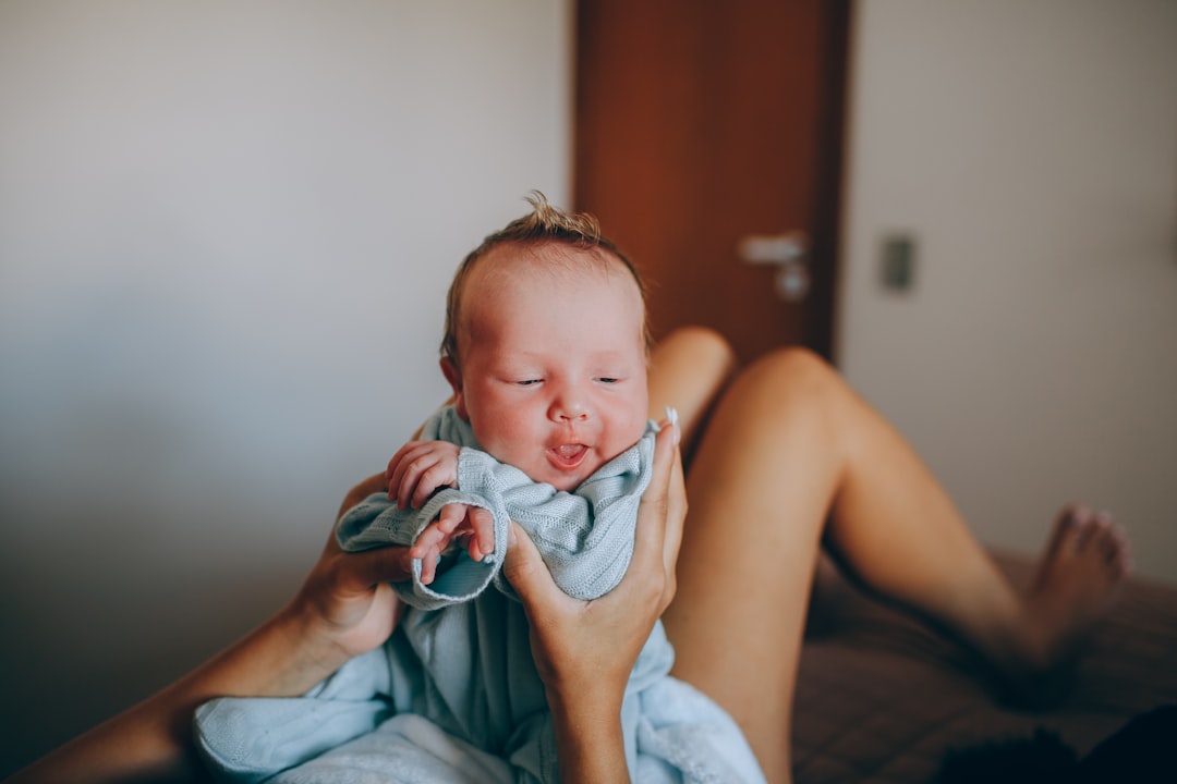 woman carrying baby in blue and white onesie