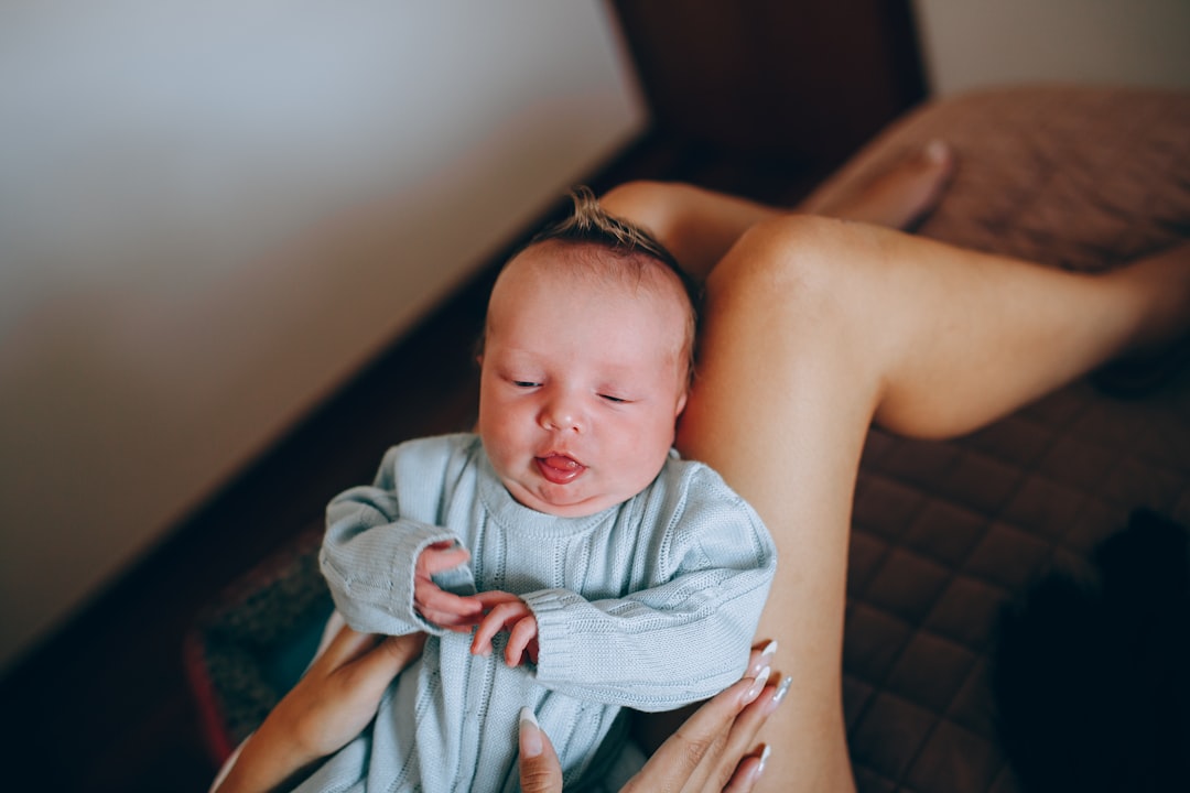 woman carrying baby in blue and white blanket,
