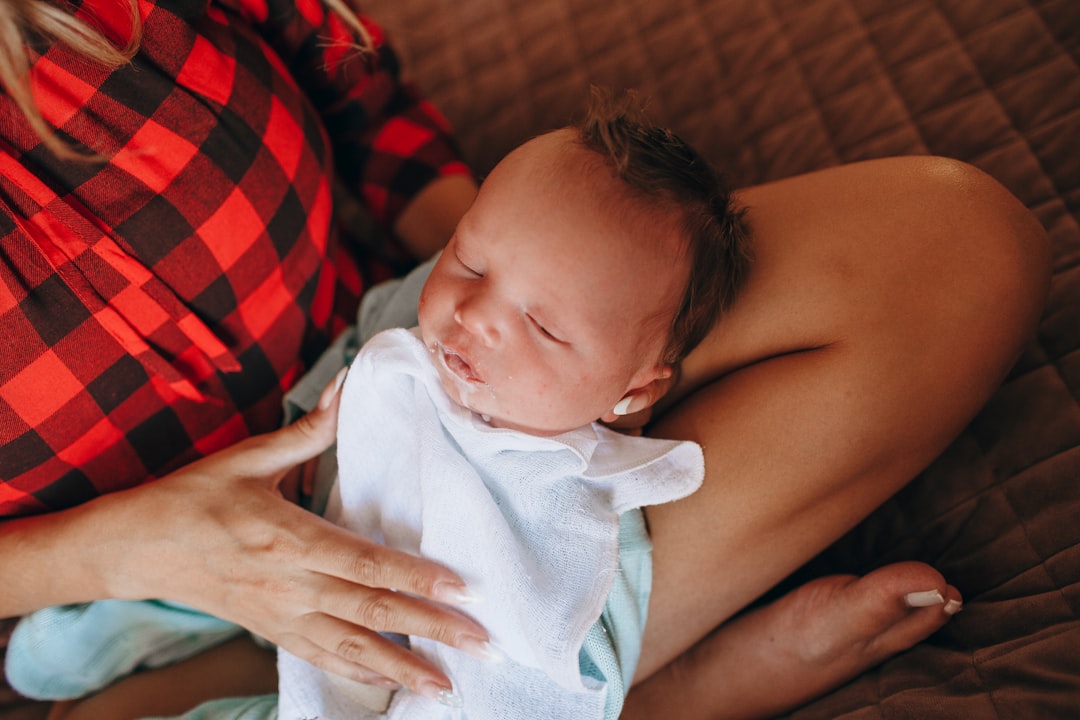 woman in red and black stripe shirt carrying baby