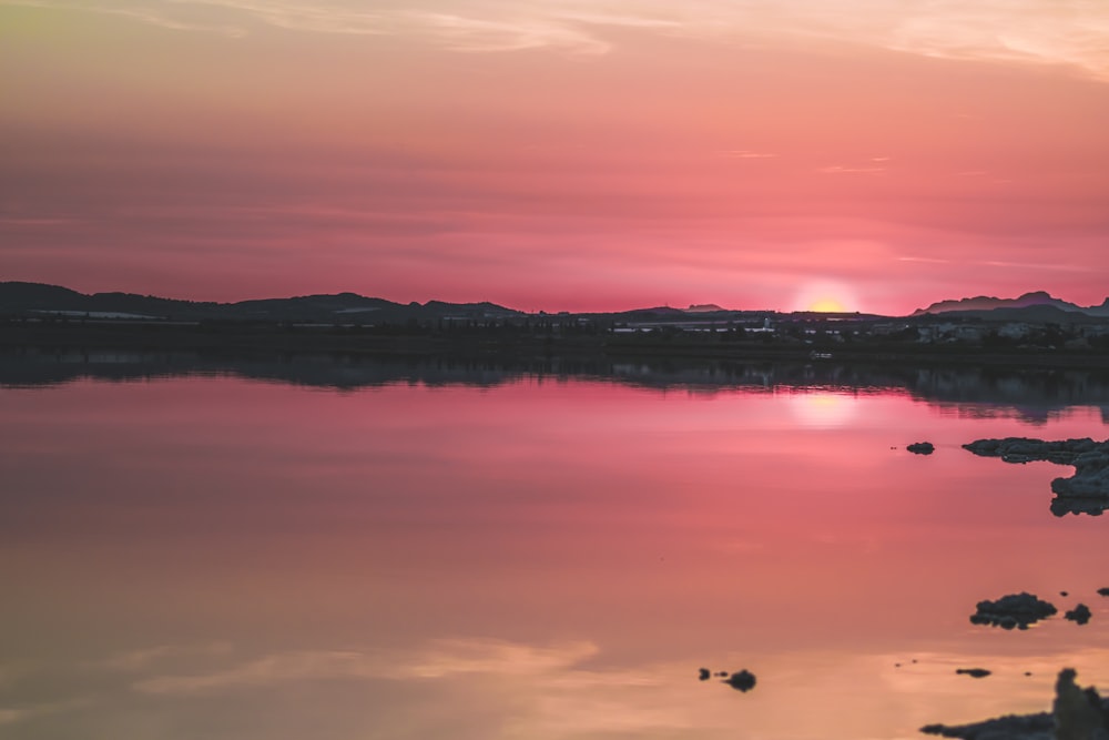 silhouette of mountains and body of water during sunset