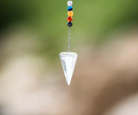 A serene crystal pendulum swinging gently over a mystical tarot card spread.