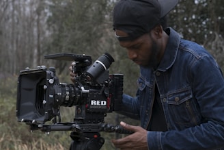 man in blue denim jacket holding black dslr camera