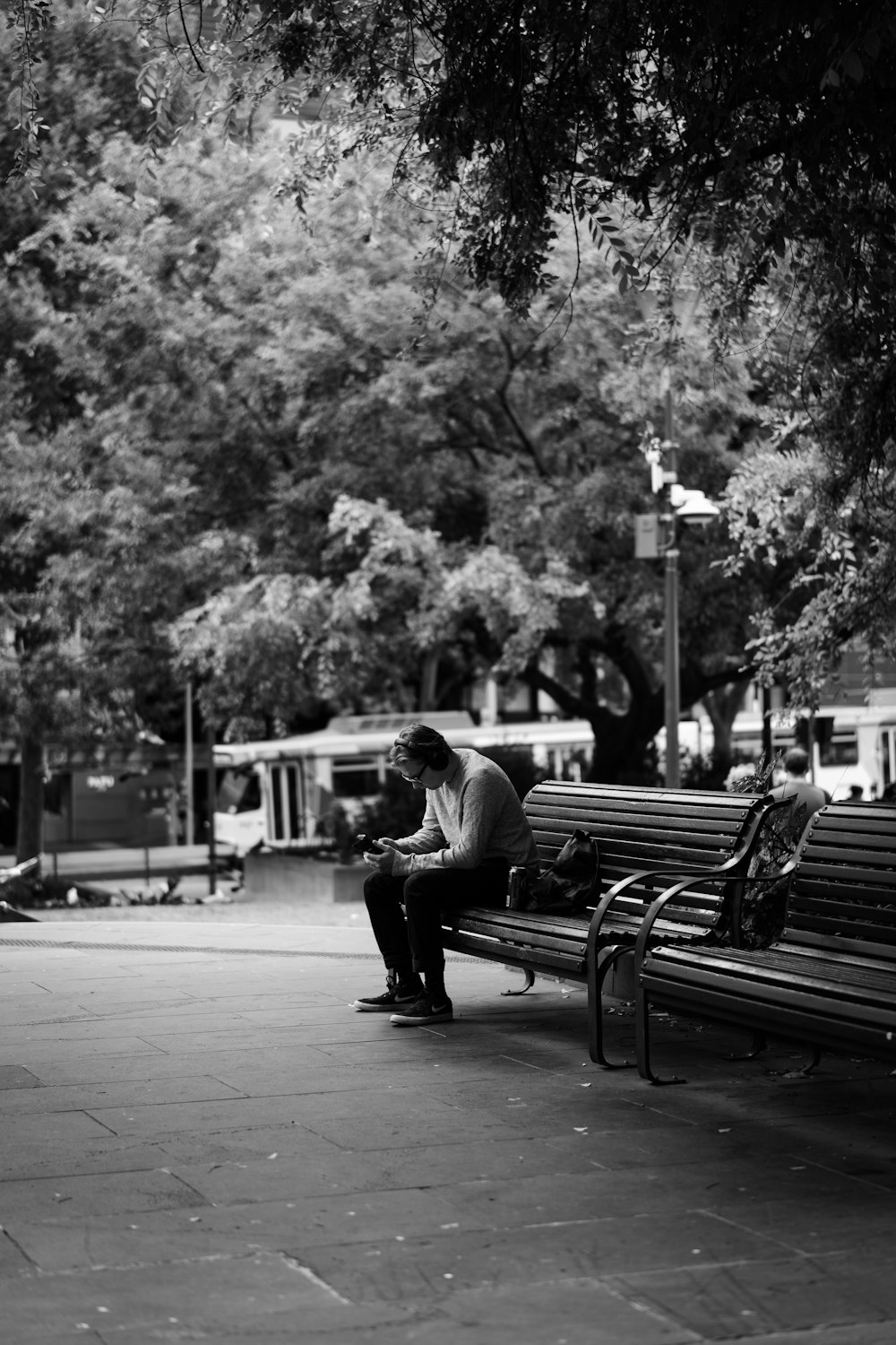 man sitting on bench in grayscale photography