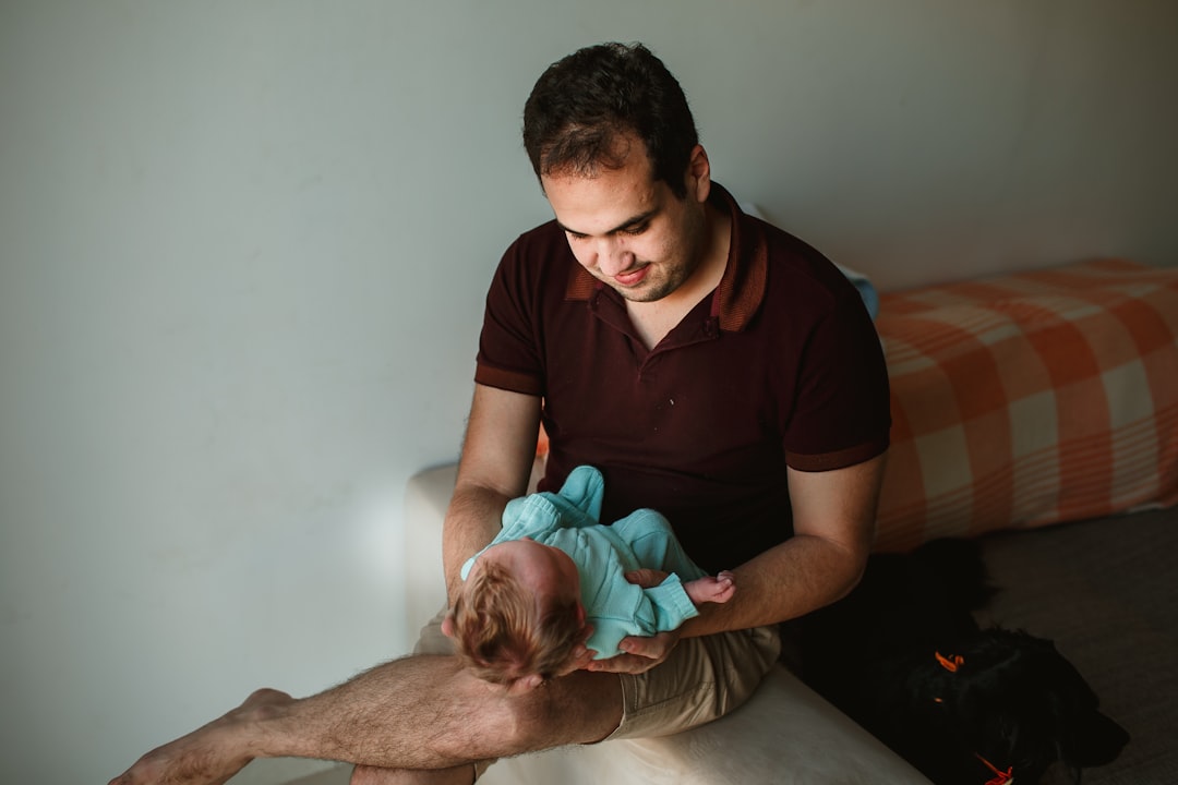 man in maroon polo shirt carrying baby