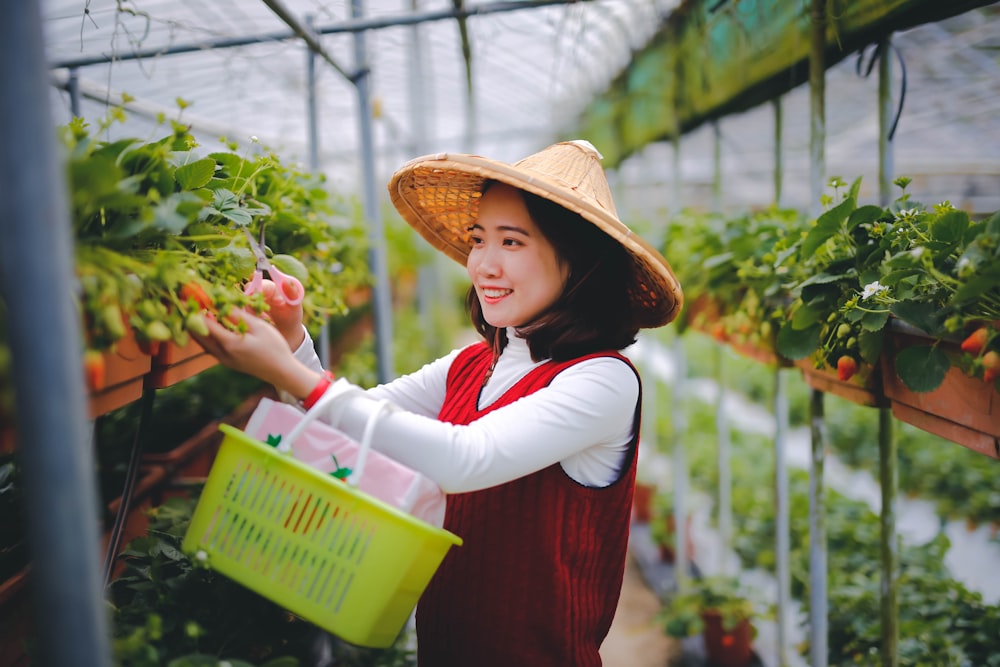 woman in red and white long sleeve shirt holding green basket with pink flowers