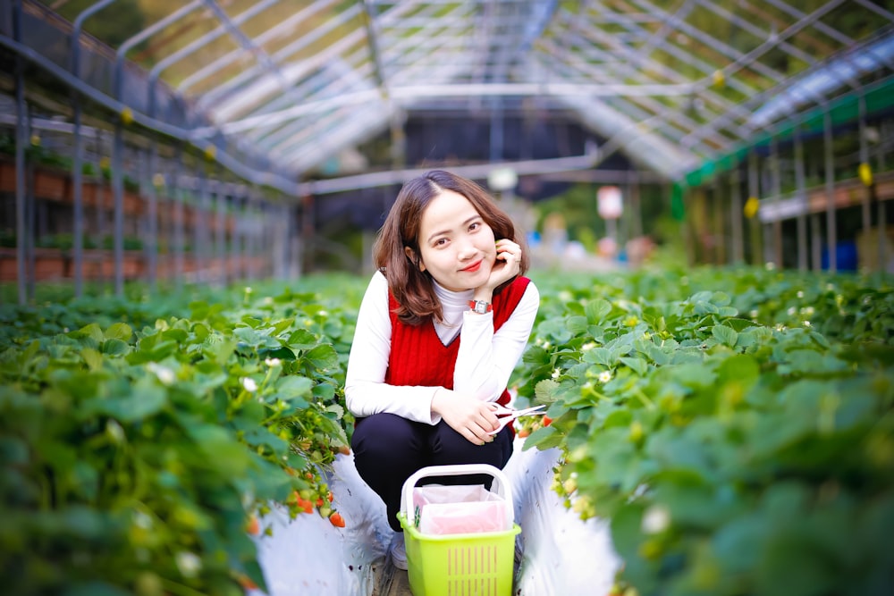 girl in white long sleeve shirt and black pants holding green plastic container