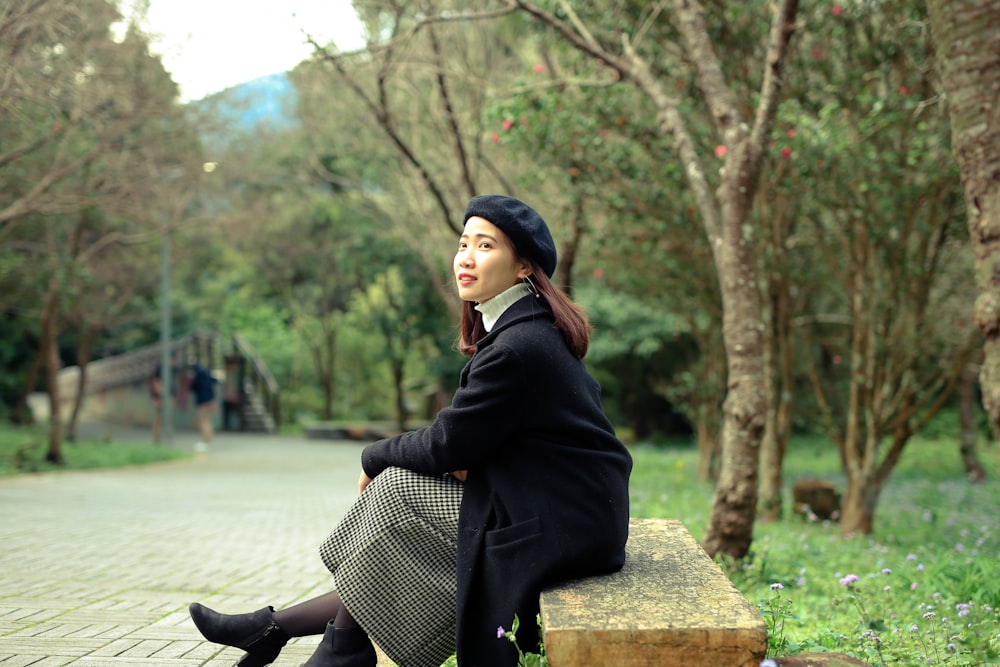 woman in black jacket sitting on brown concrete bench