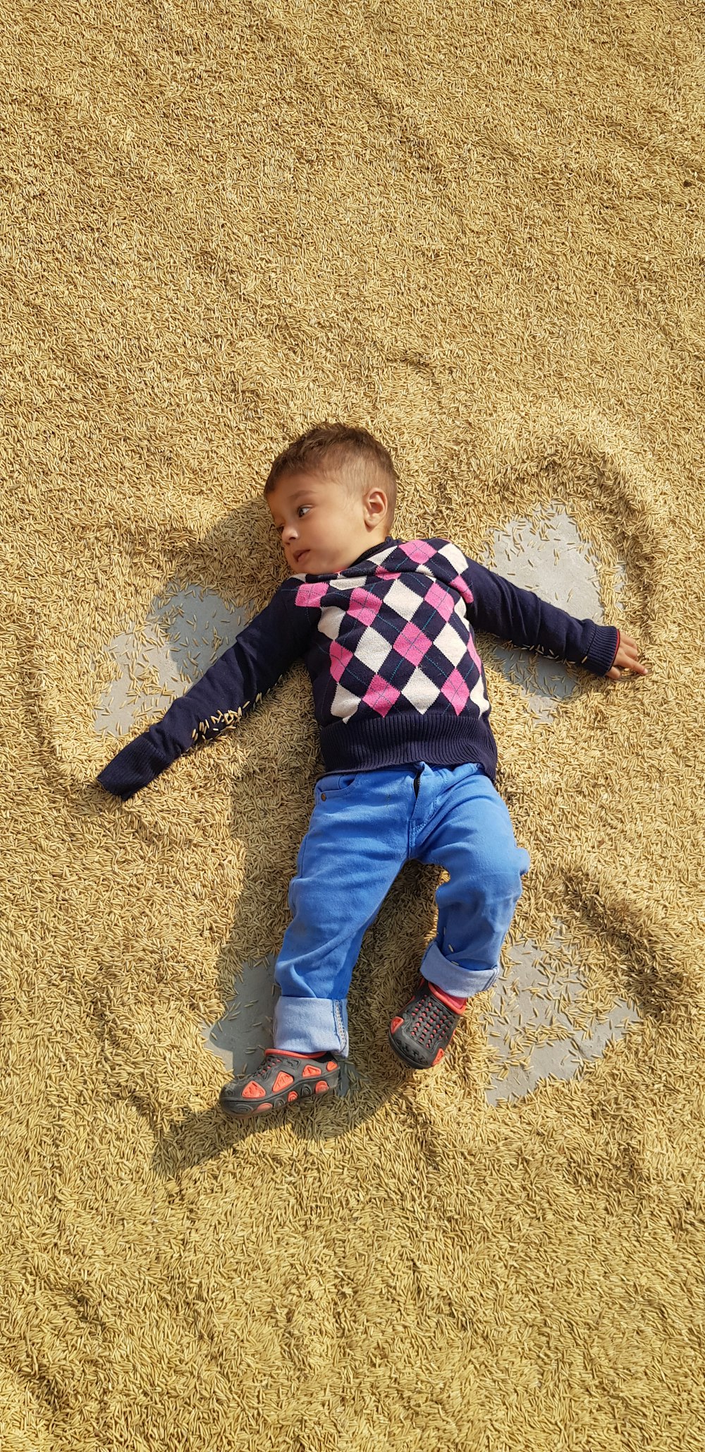 boy in blue and red striped long sleeve shirt and blue denim jeans lying on brown