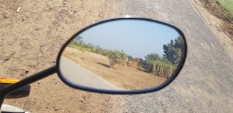 Close-up of motorcycle mirrors reflecting a scenic road