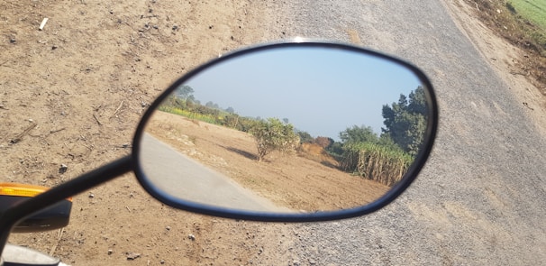 Close-up of motorcycle mirrors reflecting a scenic road