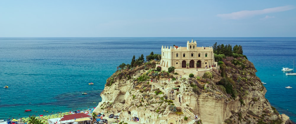 beige concrete building on cliff by the sea during daytime