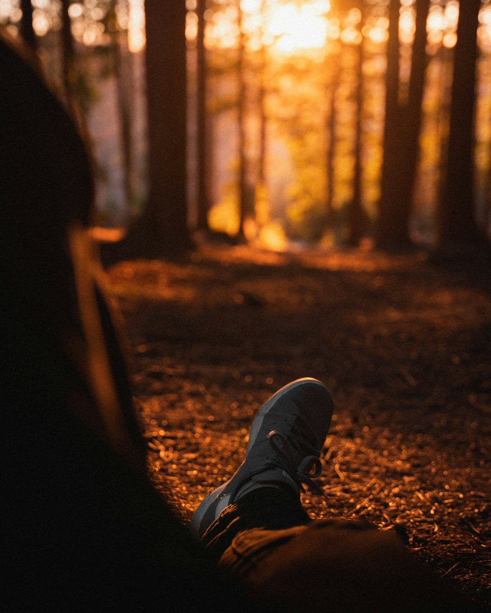 person in black pants and gray sneakers sitting on ground during daytime