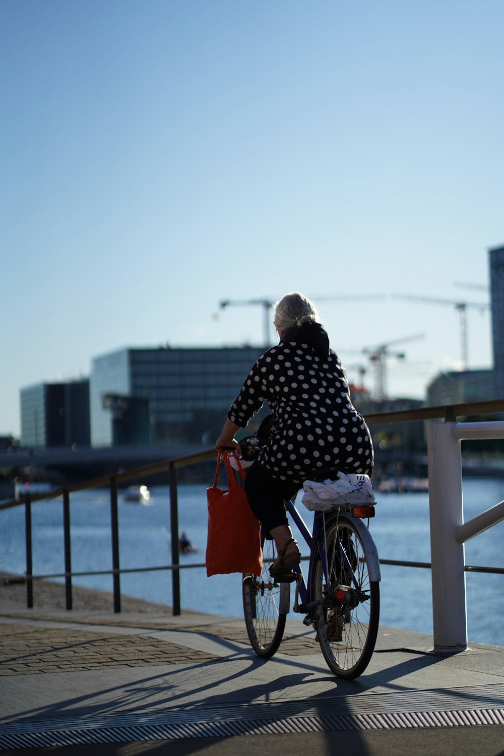 Femme en manteau à pois noir et blanc circulant sur un vélo rouge pendant la journée