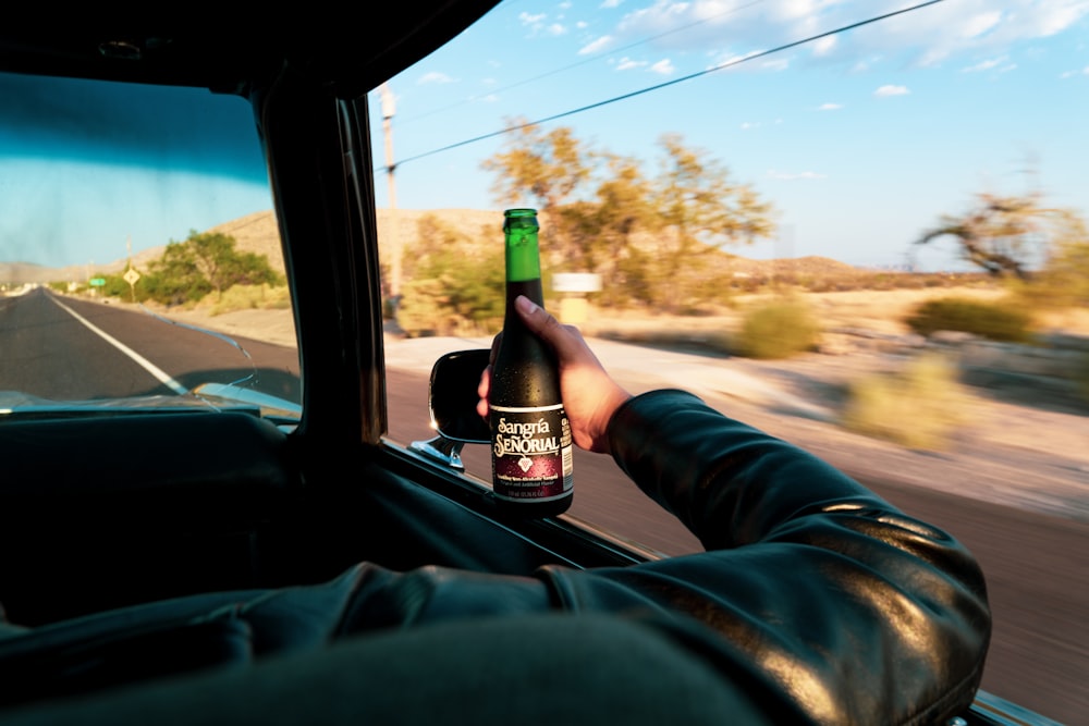 person holding black and white labeled bottle