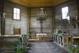 A sunlit rustic church entrance adorned with soft beige and gold floral decorations.
