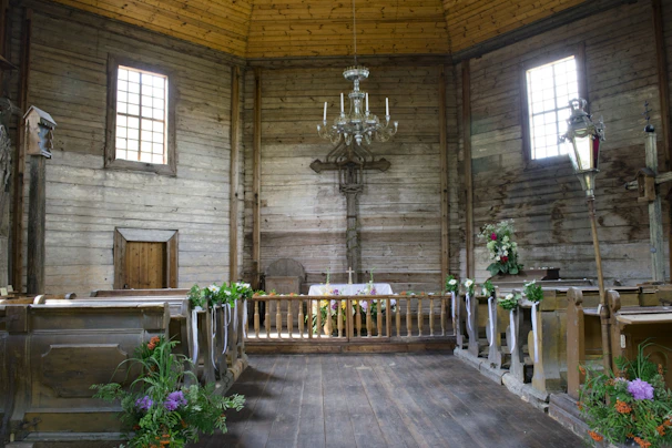 A sunlit rustic church entrance adorned with soft beige and gold floral decorations.