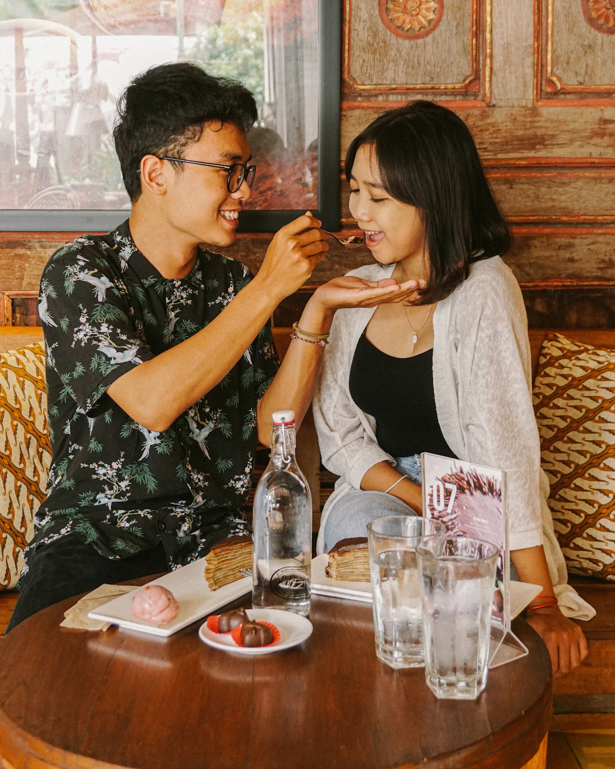 Happy couple laughing and sharing dessert and ice cream at a cafe table