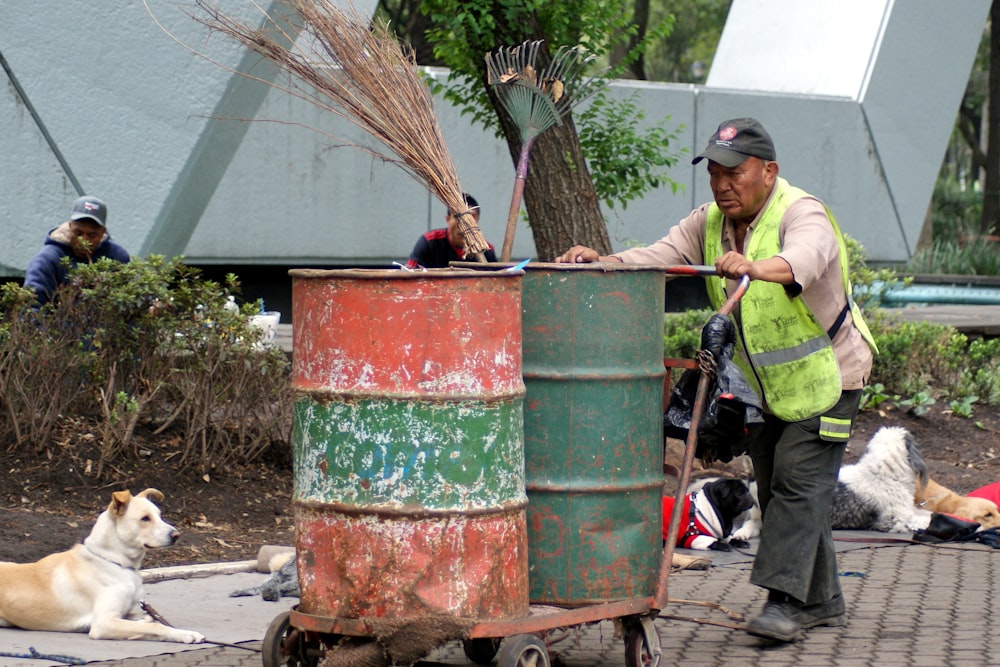 man in green polo shirt holding stick near red and green container