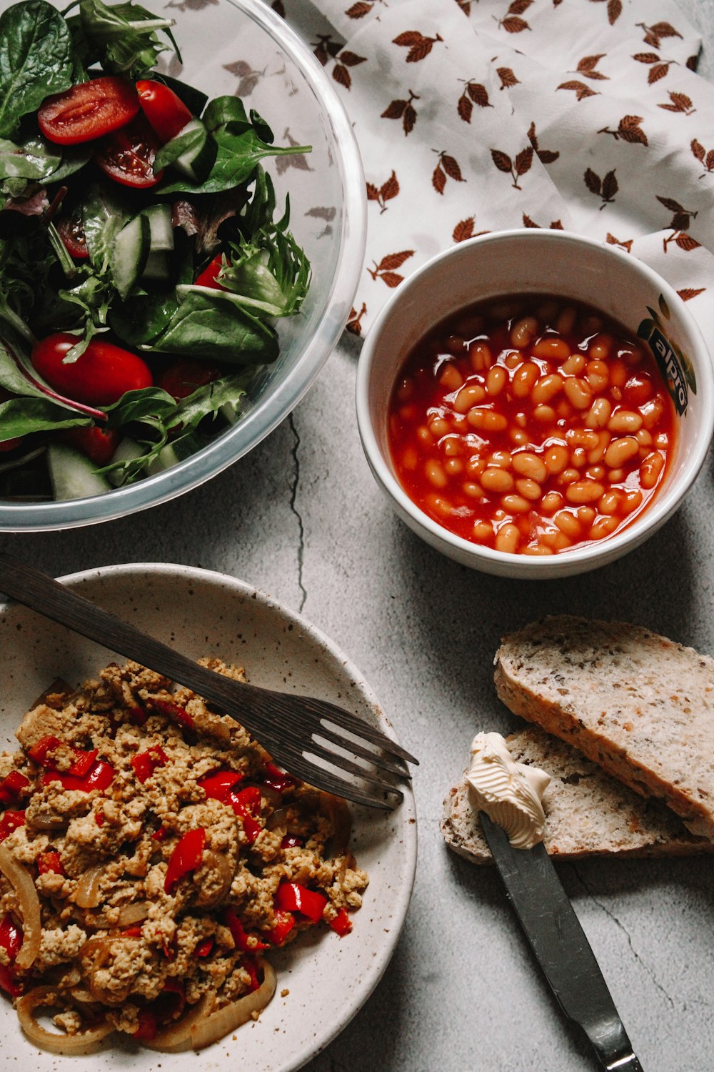 sliced bread with sliced tomatoes and green leaves on white ceramic bowl