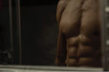 A close-up of a male fitness influencer mid-workout, muscles defined under moody lighting.