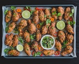 A vibrant platter featuring spicy chicken wings with dipping sauces and fresh herbs.